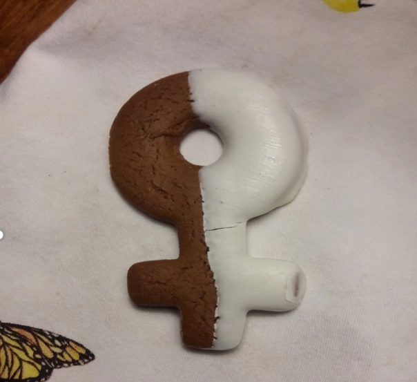 International Women’s Day cookie -- a cookie in the shape of the female symbol, half chocolate, half iced in white