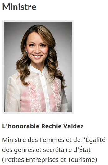 Une photo d'une femme souriante aux longs cheveux bruns ondulés, portant un chemisier blanc à broderies florales roses. Titre : « Ministre », suivi de « L'honorable Rechie Valdez » en gras, puis « Ministre des Femmes et de l'Égalité des genres et secrétaire d'État (Petites Entreprises et Tourisme) ».