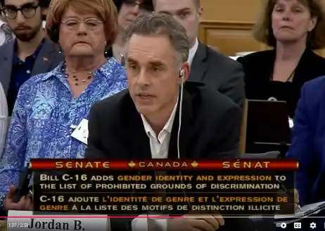 Jordan Peterson testifying before the Canadian Senate, with an on-screen graphic reading "Bill C-16 adds gender identity and expression to the list of prohibited grounds of discrimination."